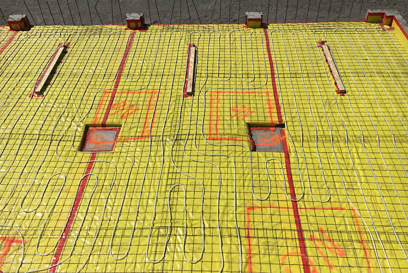 Here is another picture before concrete. The 6'&ndash;long trench drains are covered with plywood caps to keep the concrete out. The areas outlined in paint in the center of the photo with "NO" in them are exclusion zones that will let me bolt an auto lift to the floor in an area clear of the radiant heat tubing.