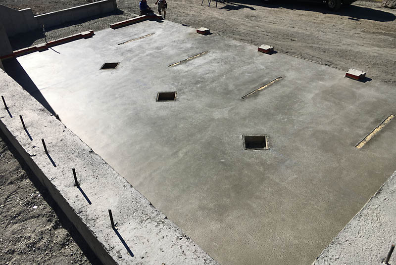 The slab has been poured. The three diamond&ndash;shaped cutouts provide access to footings for steel posts that will support a beam running the length of the garage. Once the posts are set, the voids will be filled with concrete and surround the posts.